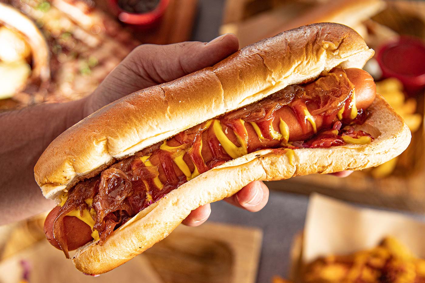 Hand Holds Dressed Hot Dog, by The BlackRabbit via Unsplash